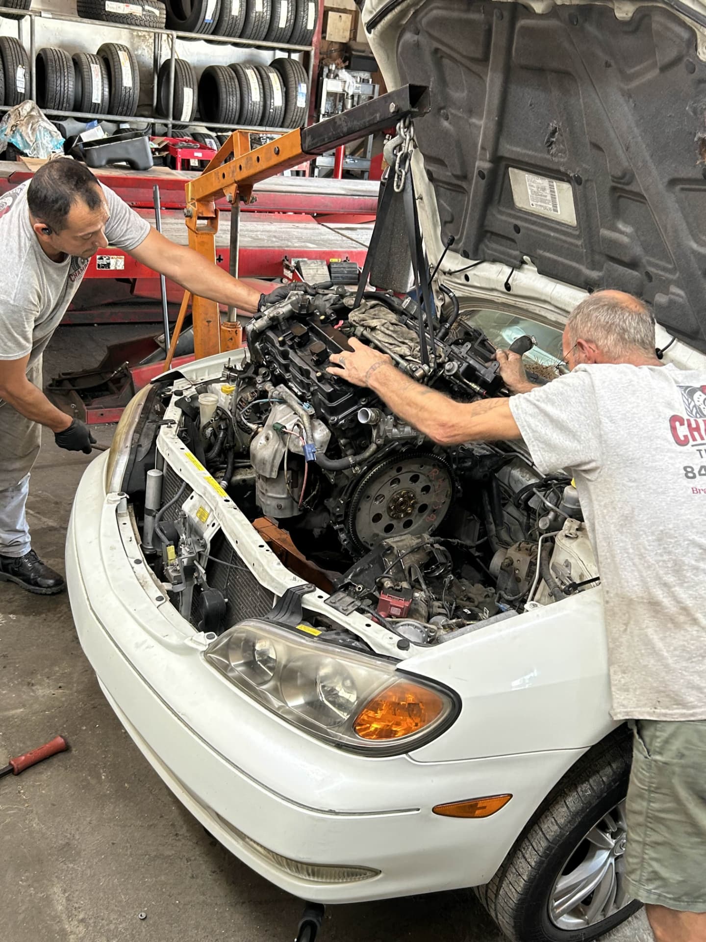 Champion mechanics lifting an engine out of a Lexus with an engine hoist during a major repair
