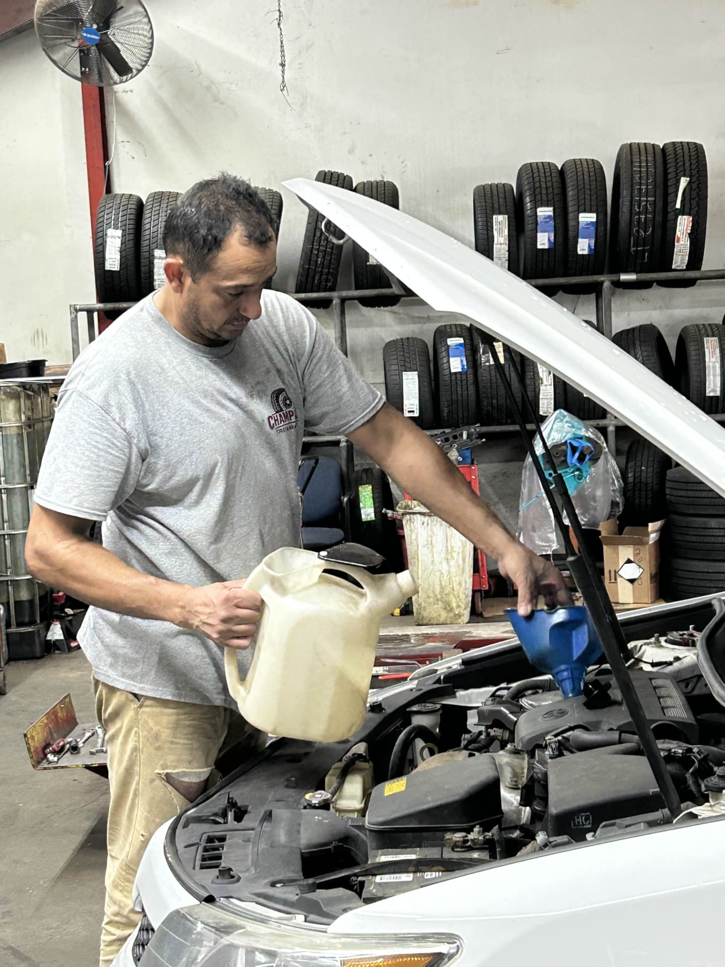 Champion Tires & Brakes technician adding fresh oil during an oil change in North Charleston