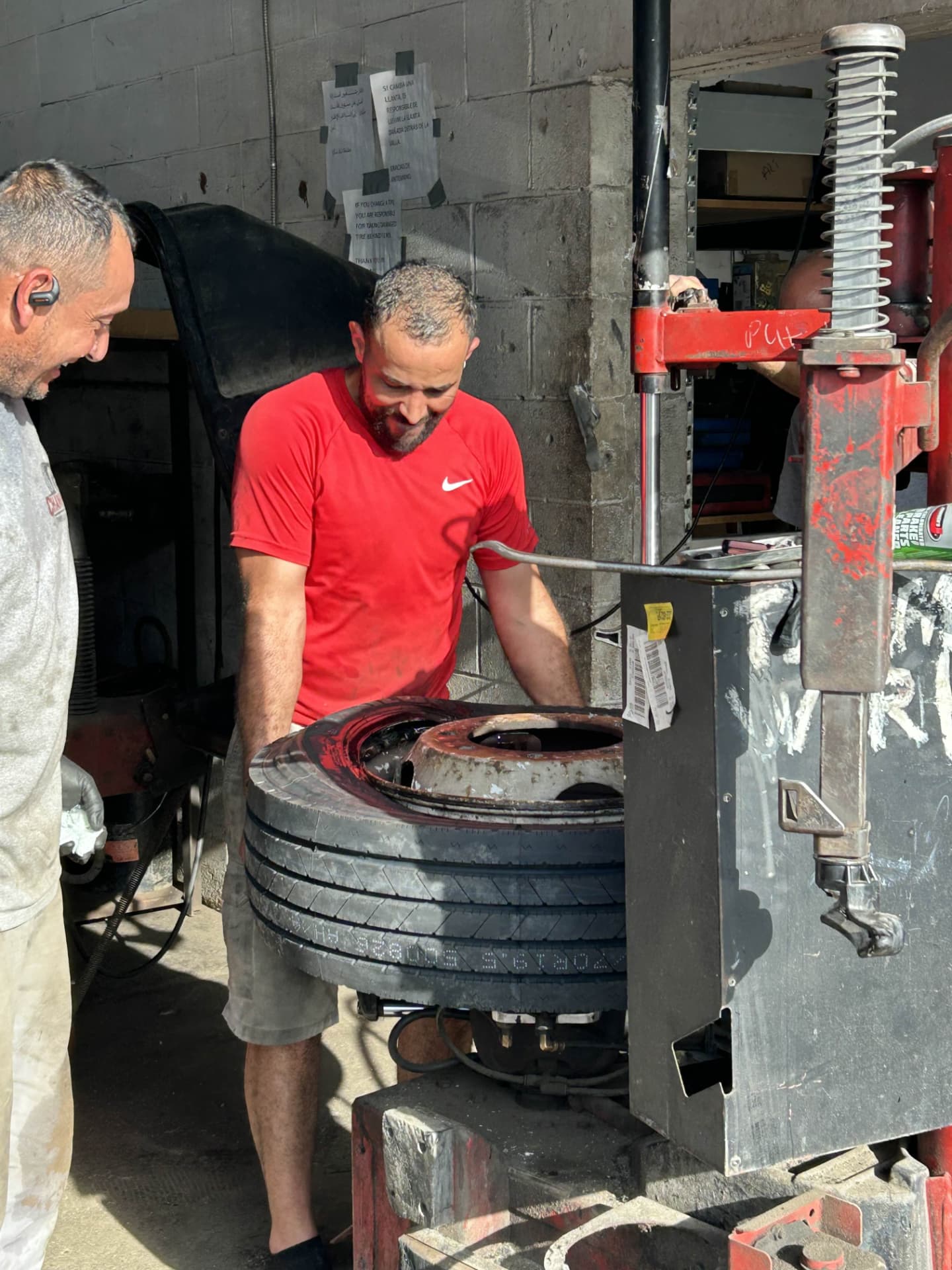 Two Champion technicians mounting a tire on the tire machine at the Rivers Avenue shop